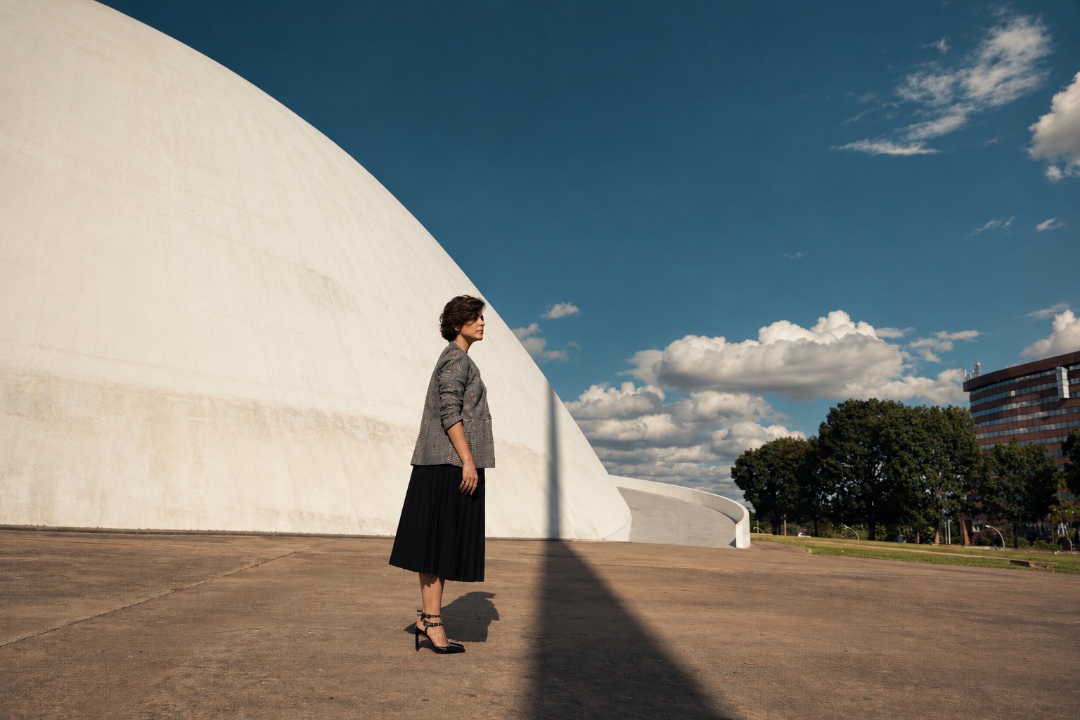 Alline Andrade de perfil diante da cúpula branca do Museu Nacional, em Brasília