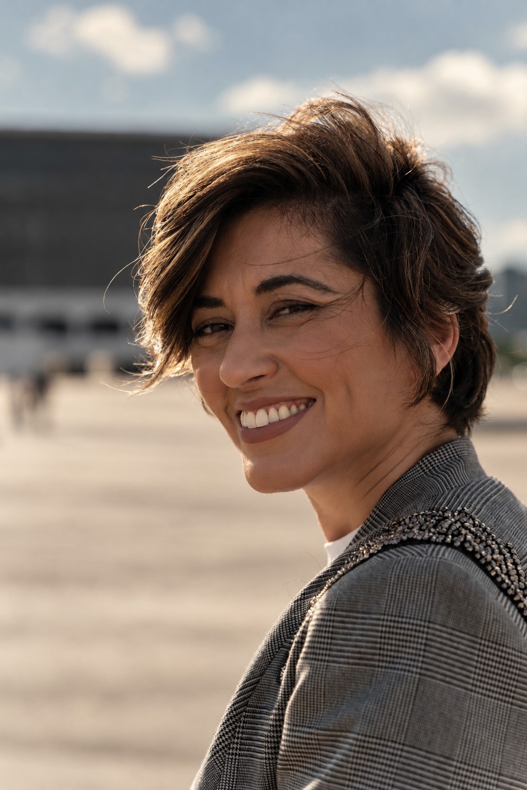 Alline Andrade de lado, sorrindo e olhando para a câmera